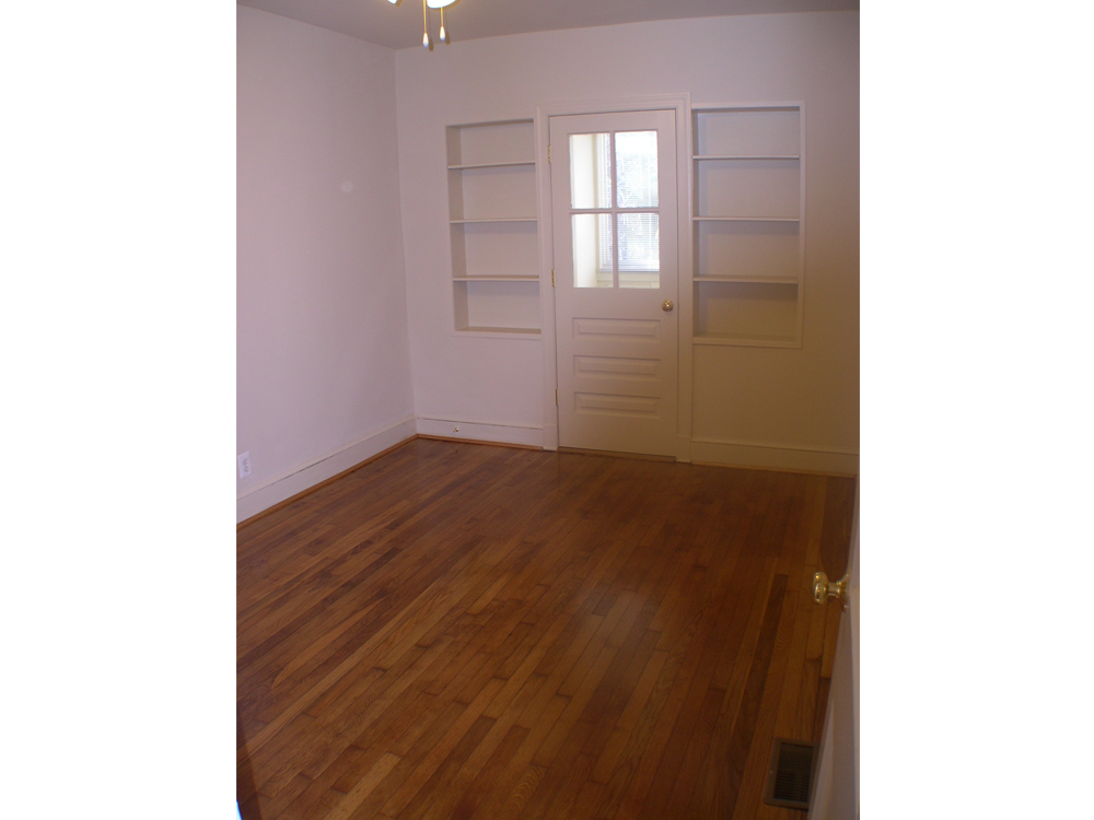 an empty living room with a wooden floor and a white door